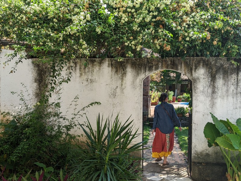 Joan Strong walking through opening in wall at Rancho Spratling